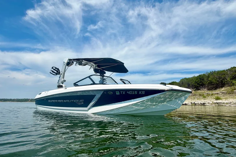 Slide: The Image of 2022 Nautique Super Air Nautique GS24 boat on a serene lake under a blue sky. - 6