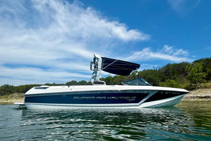 Slide: The Image of 2022 Nautique Super Air Nautique GS24 boat on a lake under a clear blue sky. - 7