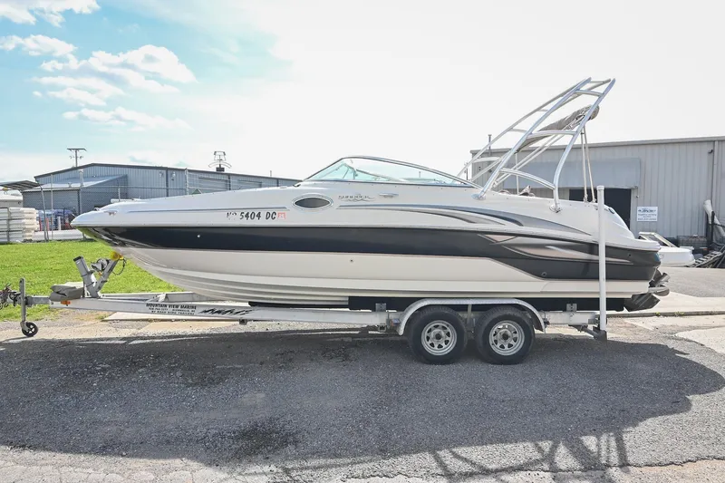The Image of 2002 Sea Ray 240 Sundeck boat on trailer, parked outdoors near industrial buildings. - 0