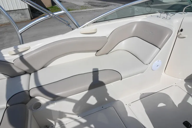 Slide: The Image of 2002 Sea Ray 240 Sundeck interior seating with beige upholstery and cup holders. - 28