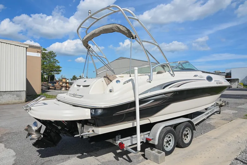 Slide: The Image of 2002 Sea Ray 240 Sundeck boat on trailer, parked outdoors under a blue sky. - 3