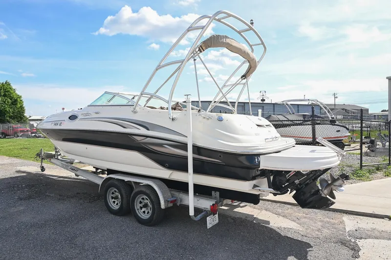 Slide: The Image of 2002 Sea Ray 240 Sundeck boat on trailer, parked outdoors under a clear sky. - 4