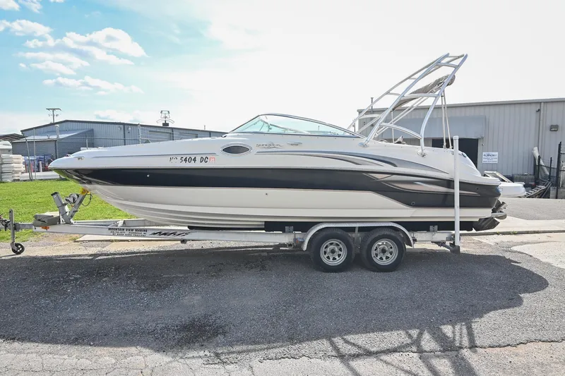 Slide: The Image of 2002 Sea Ray 240 Sundeck boat on trailer, parked outdoors near industrial buildings. - 5