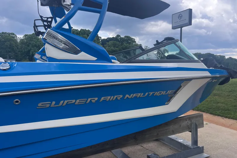 Slide: The Image of 2016 Nautique Super Air Nautique 210 boat in vibrant blue on display outdoors. - 11