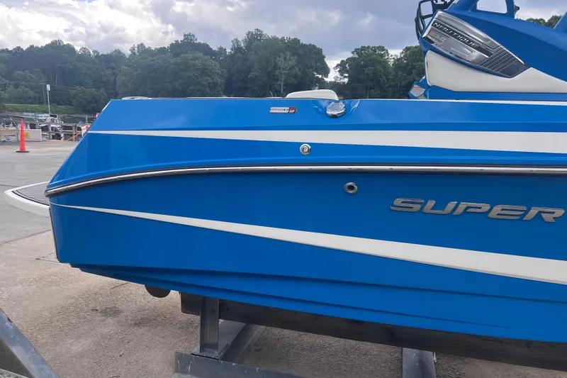 Slide: The Image of 2016 Nautique Super Air Nautique 210 boat in vibrant blue at a marina. - 12