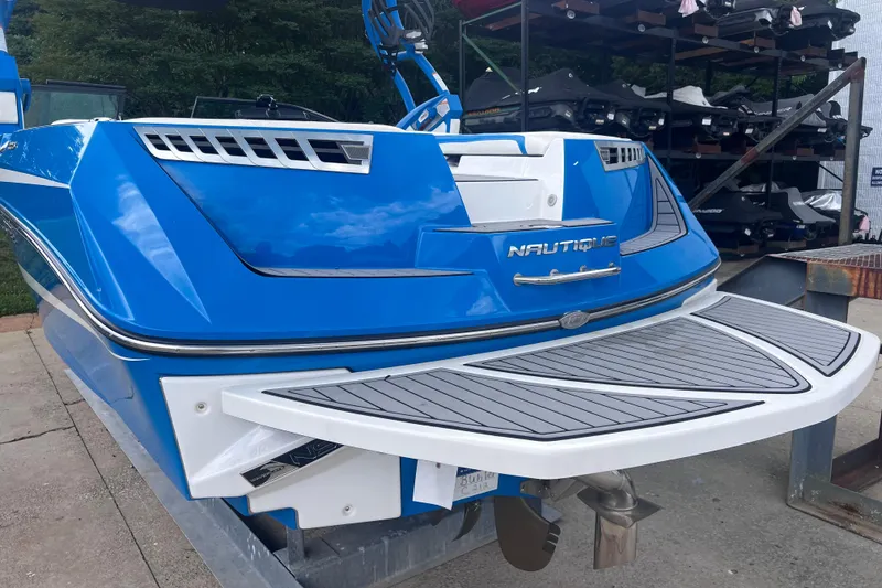 Slide: The Image of 2016 Nautique Super Air Nautique 210 boat, blue exterior, rear view on a dock. - 15