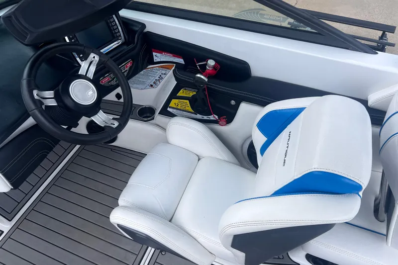 Slide: The Image of Interior of 2016 Nautique Super Air Nautique 210 boat with steering wheel and white seating. - 27