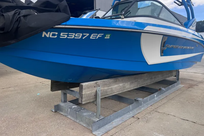 Slide: The Image of 2016 Nautique Super Air Nautique 210 boat in blue, docked on a metal stand. - 9