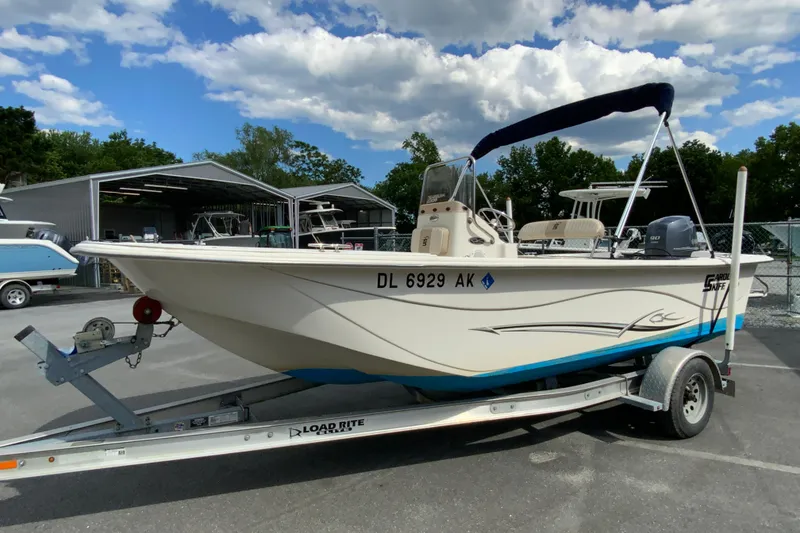 Slide: The Image of 2016 Carolina Skiff 198 DLV boat on trailer, parked outdoors under a cloudy sky. - 10