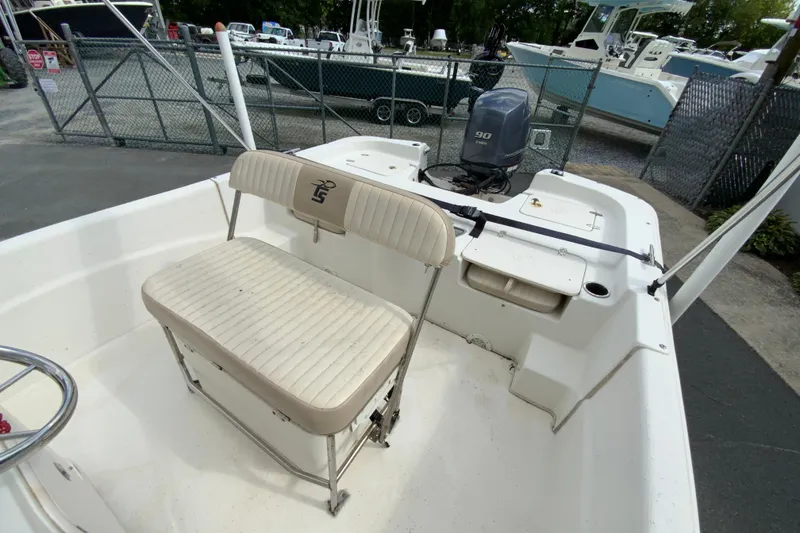 Slide: The Image of 2016 Carolina Skiff 198 DLV boat interior with seating and motor, parked in a marina. - 19