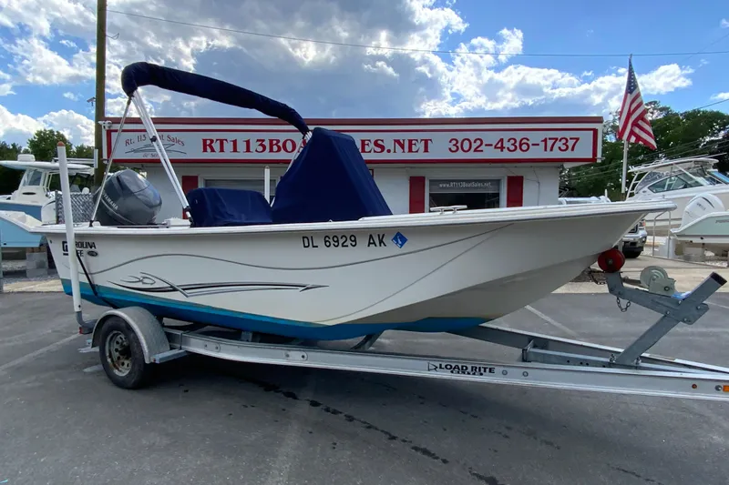 Slide: The Image of 2016 Carolina Skiff 198 DLV boat on trailer at dealership with American flag. - 2
