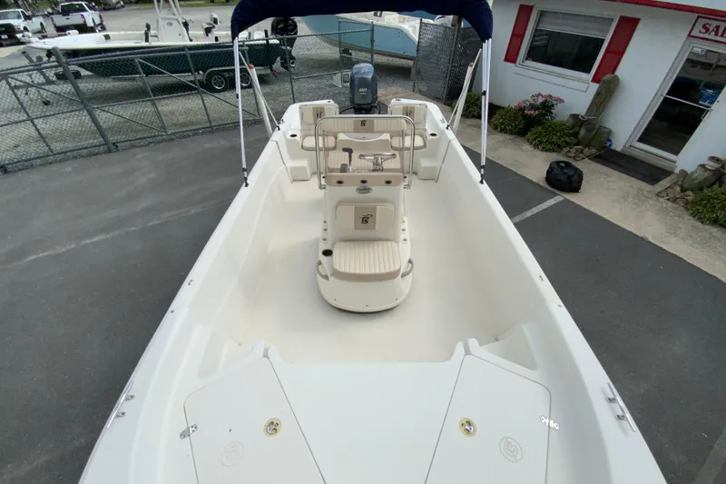 Slide: The Image of 2016 Carolina Skiff 198 DLV boat interior with seating and console, parked outdoors. - 21