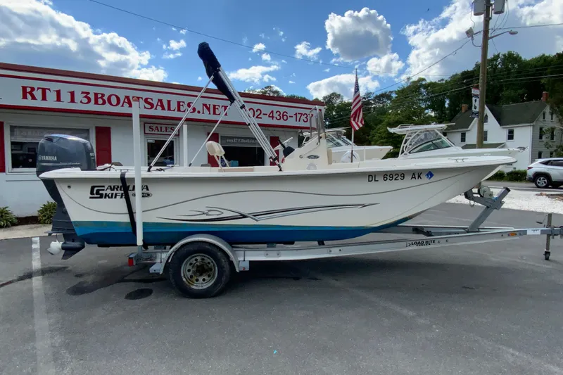 Slide: The Image of 2016 Carolina Skiff 198 DLV boat on trailer at dealership, clear sky background. - 6