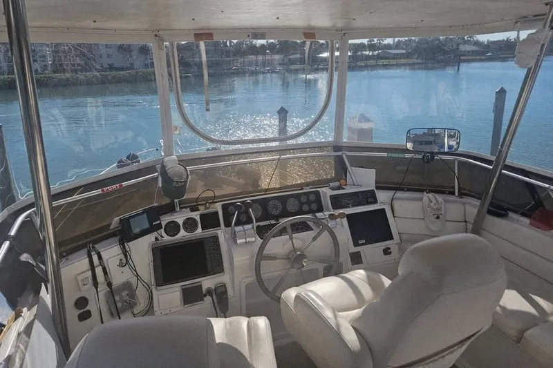 Slide: The Image of 1998 Mainship 47 Motor Yacht helm with steering wheel, controls, and water view. - 26