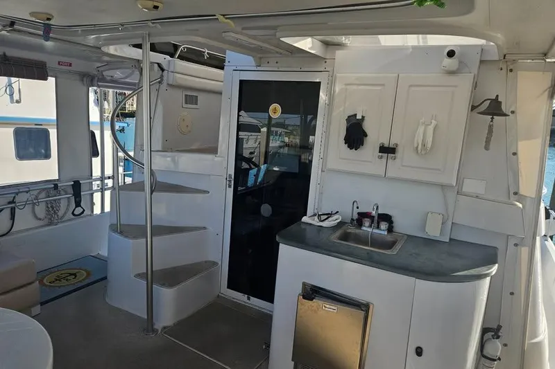 Slide: The Image of 1998 Mainship 47 Motor Yacht interior with kitchenette, spiral staircase, and outdoor seating area. - 32