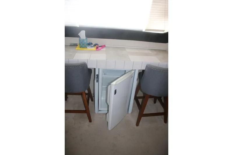 Slide: The Image of Interior of 1998 Mainship 47 Motor Yacht with open mini fridge and bar stools. - 35
