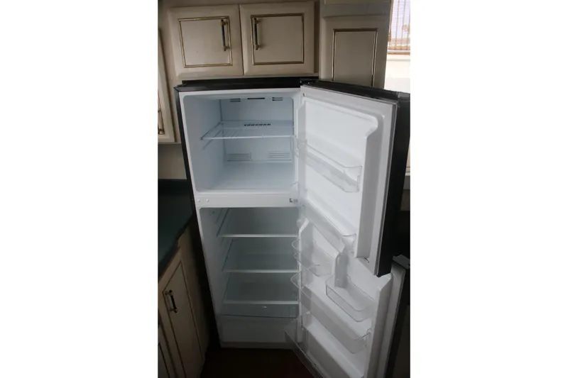 Slide: The Image of Open refrigerator inside 1998 Mainship 47 Motor Yacht, showcasing spacious interior and shelving. - 37