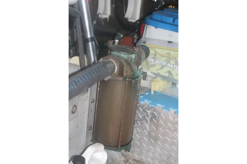 Slide: The Image of Engine compartment of a 1998 Mainship 47 Motor Yacht, featuring a metal cylinder and hoses. - 43