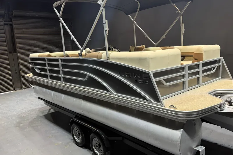 Slide: The Image of 2024 Lowe SS 230 pontoon boat with beige seating and sleek design in a showroom. - 3