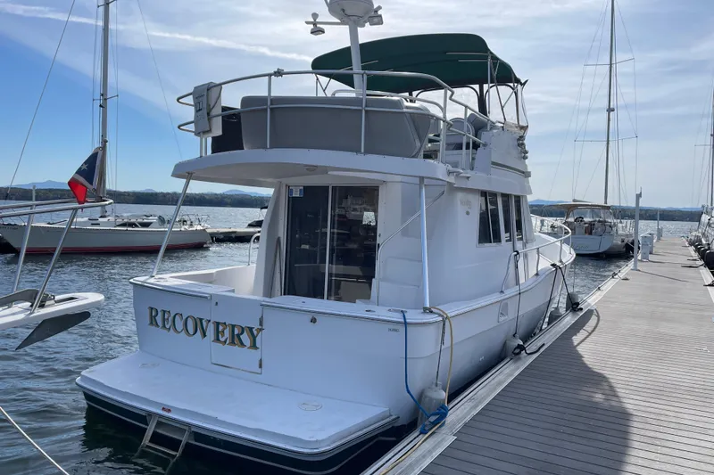 Slide: The Image of 2000 Mainship 390 Trawler docked, featuring "Recovery" nameplate, with clear skies and calm waters. - 3