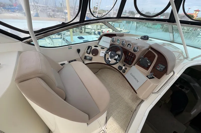 Slide: The Image of 2004 Carver 560 Voyager helm with Garmin navigation, beige seating, and marina view. - 34