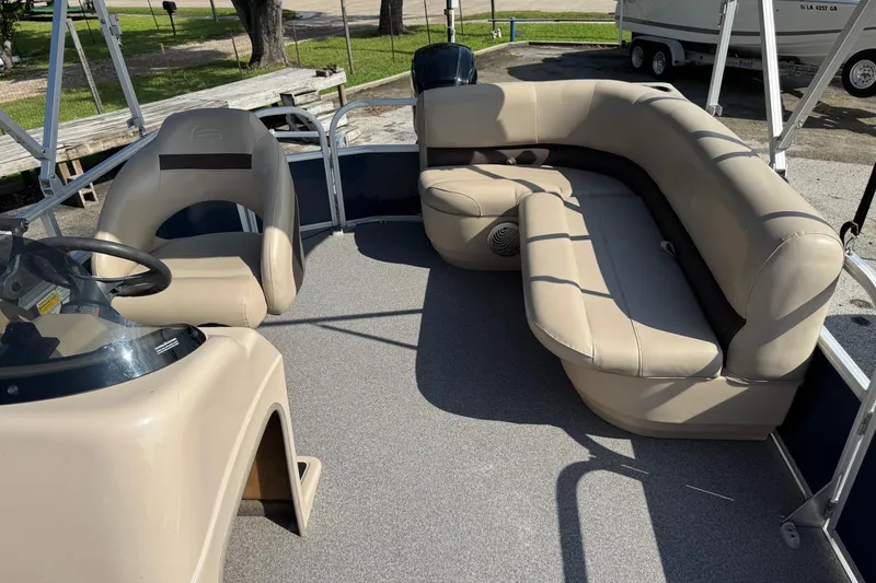 Slide: The Image of 2019 Sun Tracker Party Barge 18 DLX interior with beige seating and steering console. - 13