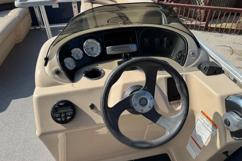 Slide: The Image of 2019 Sun Tracker Party Barge 18 DLX dashboard with steering wheel and gauges. - 18