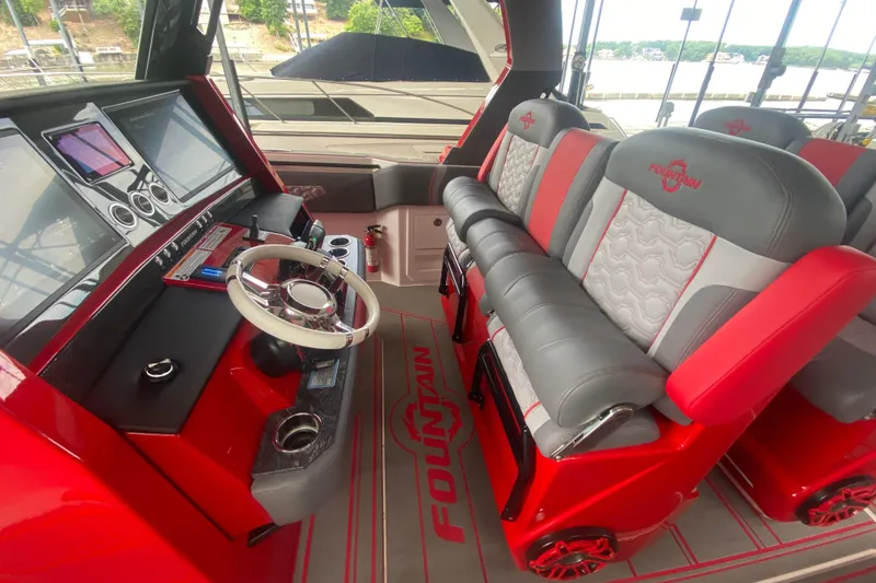 Slide: The Image of 2025 Fountain 38 SCX boat interior with red and gray seating, modern dashboard, and steering wheel. - 16