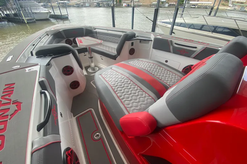 Slide: The Image of 2025 Fountain 38 SCX boat interior with red and gray seating, docked by the water. - 21
