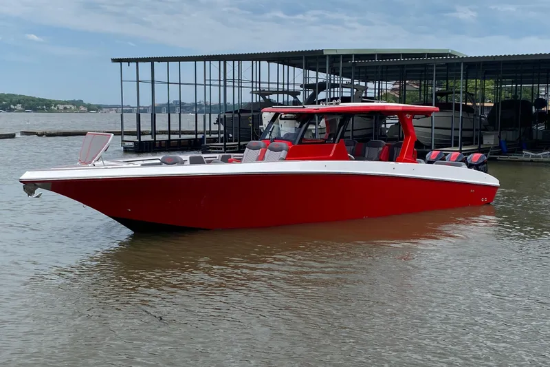 Slide: The Image of Red 2025 Fountain 38 SCX boat docked on a calm lake under a cloudy sky. - 4