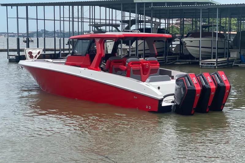 Slide: The Image of 2025 Fountain 38 SCX boat with red and white design, docked on a calm lake. - 5