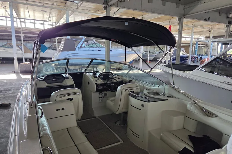 Slide: The Image of 2005 Sea Ray 270 SLX boat interior with seating and helm, docked in a marina. - 4