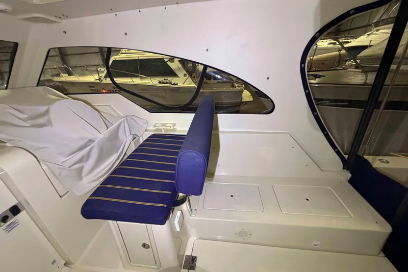Slide: The Image of Interior of 2005 Mainship Pilot 34 boat with blue-striped seating and large windows. - 10