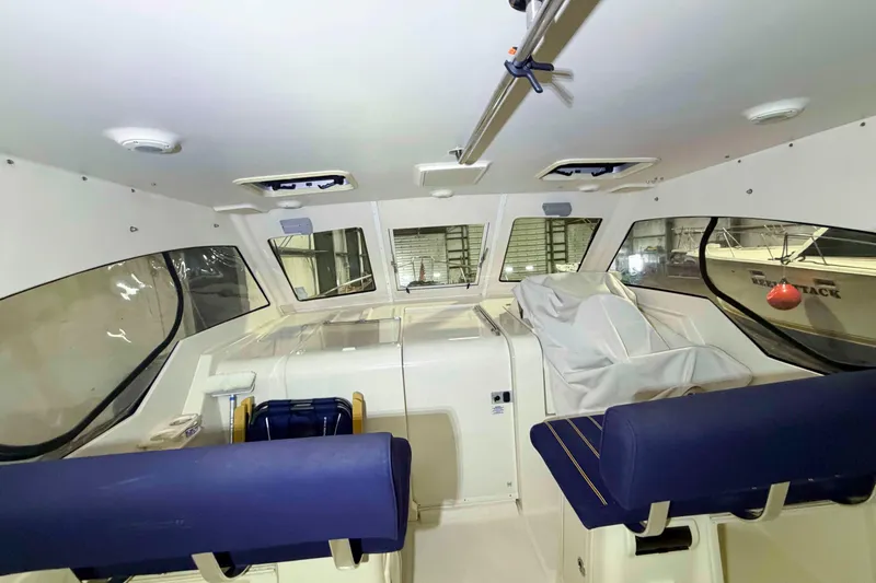 Slide: The Image of Interior view of a 2005 Mainship Pilot 34 boat with blue seating and large windows. - 12