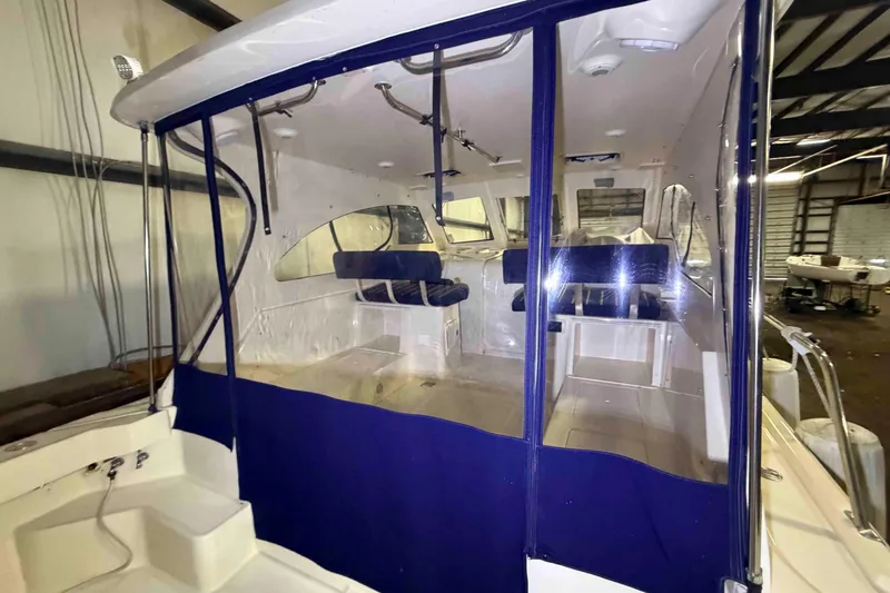 Slide: The Image of 2005 Mainship Pilot 34 boat interior with blue seating and clear enclosure. - 13