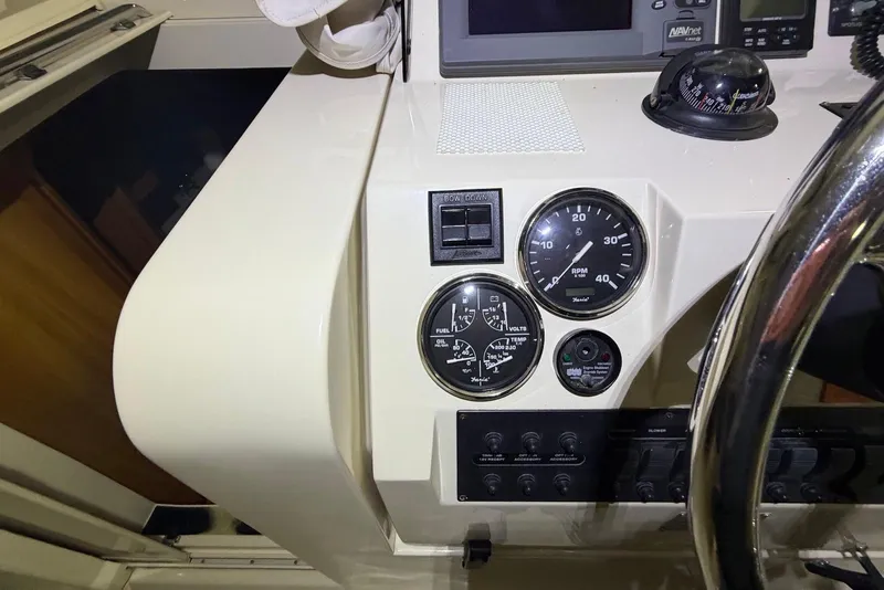 Slide: The Image of 2005 Mainship Pilot 34 dashboard with gauges and controls, featuring a steering wheel and navigation equipment. - 24