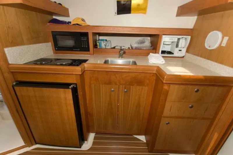 Slide: The Image of 2005 Mainship Pilot 34 galley with wood cabinetry, microwave, stove, sink, and refrigerator. - 30