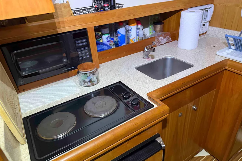 Slide: The Image of Compact kitchen in 2005 Mainship Pilot 34 boat with stove, microwave, and sink. - 31