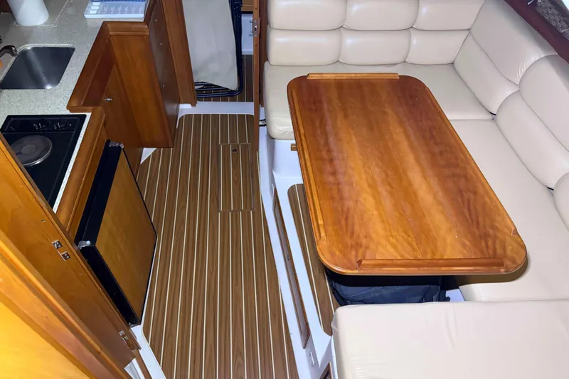 Slide: The Image of 2005 Mainship Pilot 34 interior with wooden table, kitchenette, and cushioned seating. - 33