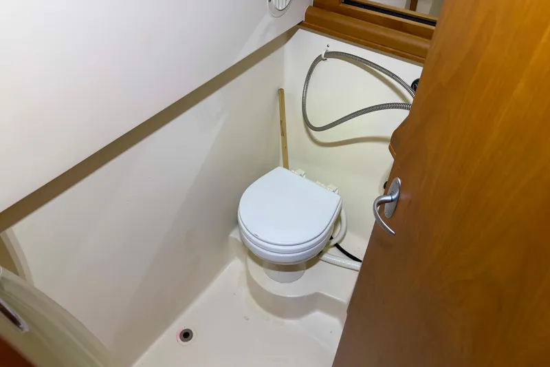 Slide: The Image of 2005 Mainship Pilot 34 boat bathroom with toilet and wooden door. - 39