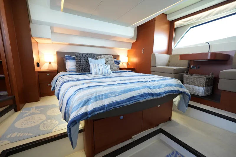 Slide: The Image of Luxurious 2015 Prestige 500S yacht bedroom with striped bedding and elegant wood accents. - 1