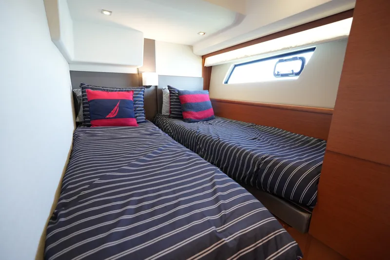Slide: The Image of Twin beds in a 2015 Prestige 500S yacht cabin with striped bedding and nautical-themed pillows. - 62