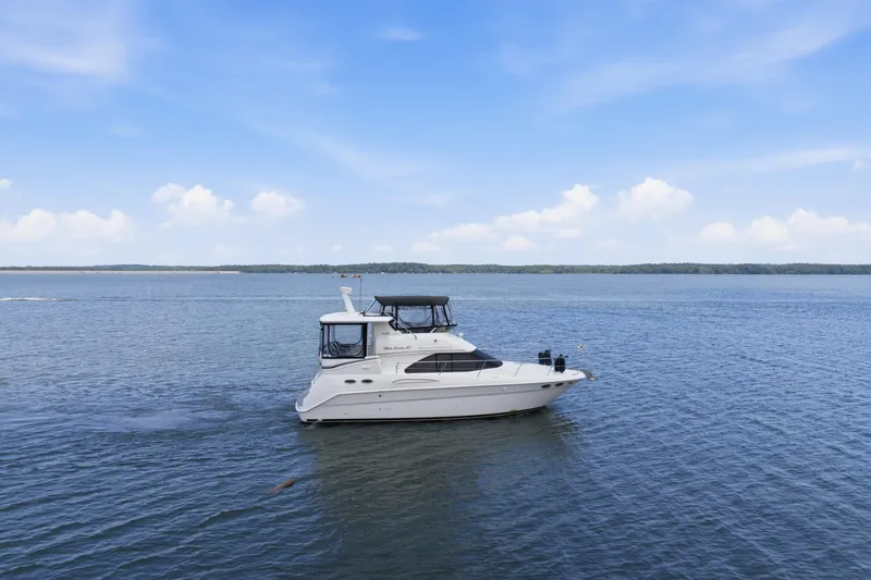 Slide: The Image of 1997 Sea Ray 370 Aft Cabin yacht cruising on a calm lake under a clear blue sky. - 0