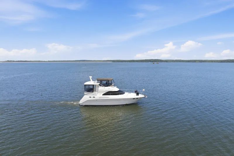 Slide: The Image of 1997 Sea Ray 370 Aft Cabin cruising on a calm lake under a clear blue sky. - 1