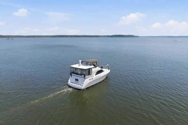 Slide: The Image of 1997 Sea Ray 370 Aft Cabin cruising on a calm lake under a clear blue sky. - 10