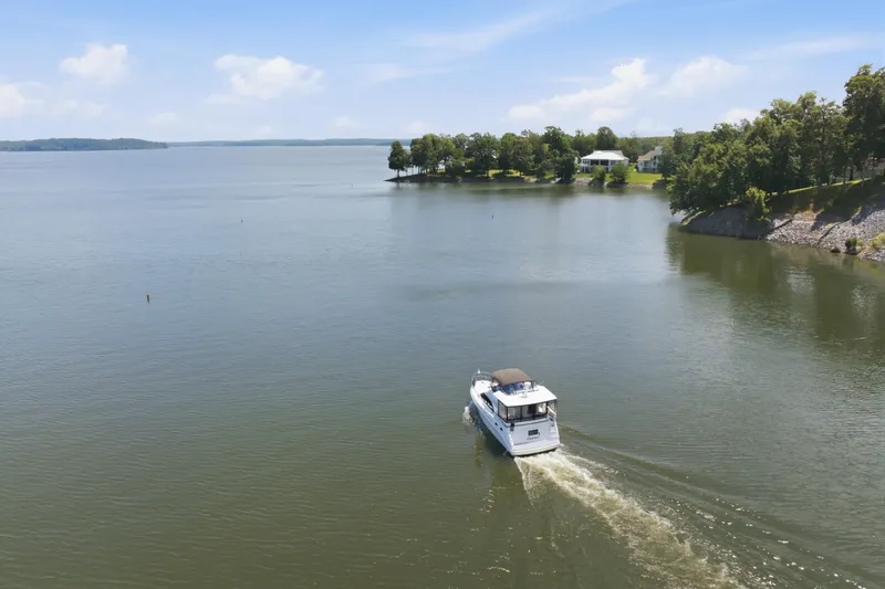 Slide: The Image of 1997 Sea Ray 370 Aft Cabin cruising on a serene lake with lush shoreline. - 12