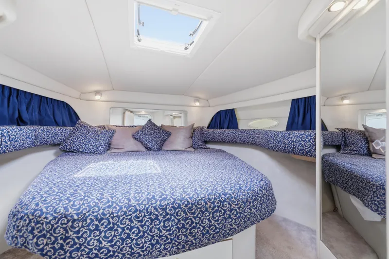 Slide: The Image of Luxurious 1997 Sea Ray 370 Aft Cabin bedroom with blue patterned bedding and skylight. - 33
