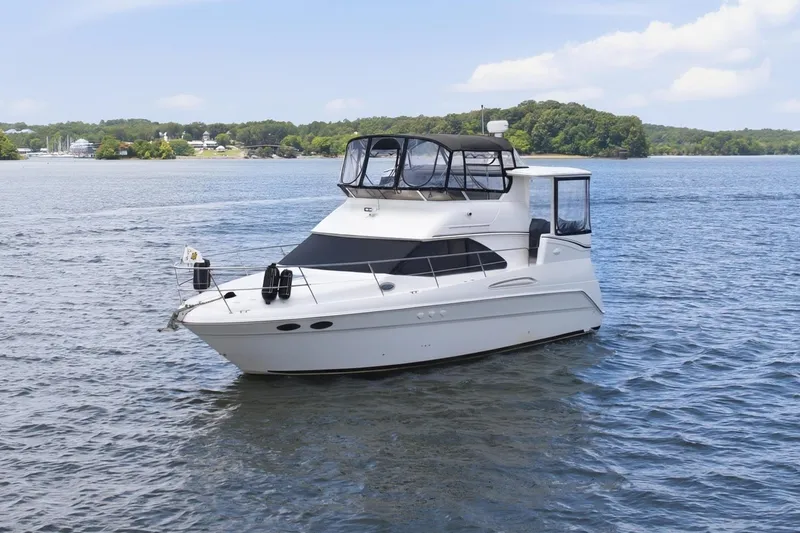 Slide: The Image of 1997 Sea Ray 370 Aft Cabin yacht cruising on a serene lake under a clear blue sky. - 5