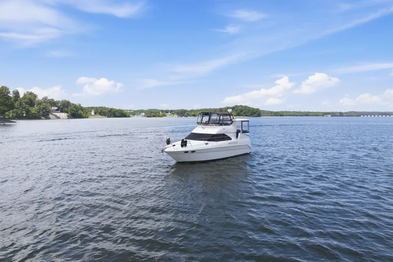 Slide: The Image of 1997 Sea Ray 370 Aft Cabin yacht cruising on a serene lake under a clear blue sky. - 5