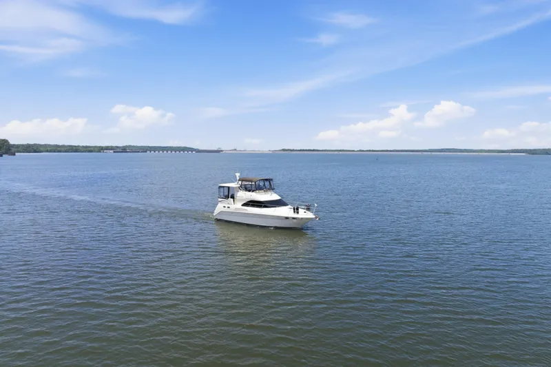Slide: The Image of 1997 Sea Ray 370 Aft Cabin yacht cruising on a serene lake under a clear blue sky. - 6